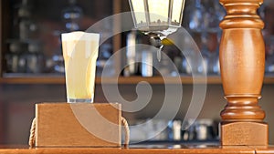 Pour beer into a transparent glass on the bar. Light, golden beer pours into a glass against the backdrop of a bar in a