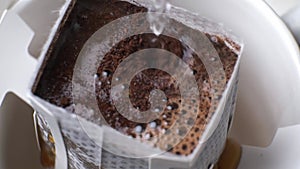 Pour boiling water into drip bag coffee, close-up.