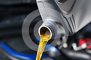Pour car lubricant from a gray bottle on the background of the engine. Oil change service, auto repair shop Technology and