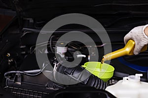 Pour car lubricant from a gray bottle on the background of the engine. Oil change service, auto repair shop Technology and