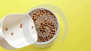 Pour cat food into a bowl, top view. Pet food