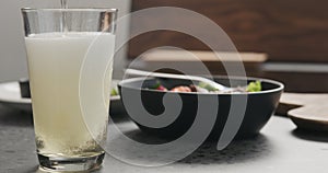 Pour cider into pint glass with salad bowl on a background