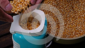 Pour the corn into the popcorn machine. Closeup food video 4k
