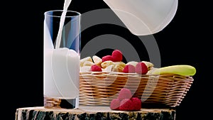 Pour fresh milk into a glass on a black background, dairy products with fruits in a basket, white fruit yogurt