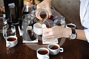 Pour freshly brewed coffee from a glass jug on white cups