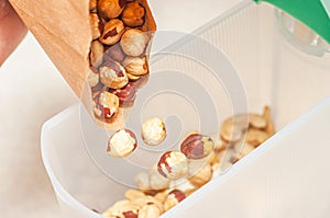 Pour hazelnuts in one bowl with cashew nuts to create an assortment of nuts for a balanced diet