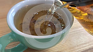 Pour herbal tea into a cup of green tea with blue cornflowers. Carpathian hot drink during the cold season, traditional