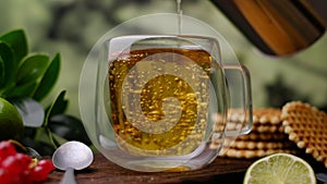 Pour herbal tea into a glass. Close-up 4k video shooting, on a dark background