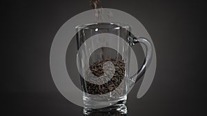 Pour loose leaf tea into a glass mug. Slow motion