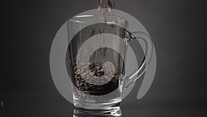 Pour loose leaf tea into a glass mug. Slow motion