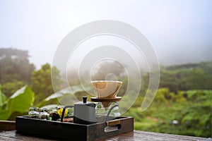 Pour-over coffee set on wooden table over blurred beautiful green mountain view