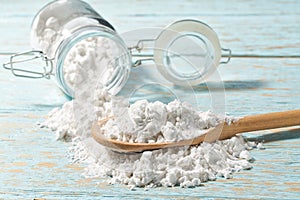 Pour  cornstarch from a glass jar into a wooden spoon, close-up