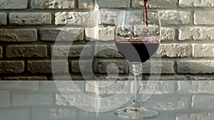 Pour red wine glass against a brick wall background,alcoholic drink grape red,close-up.