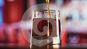Pour refreshing cold cola drink into glassful with ice cubes at party. 4k Dragon RED camera