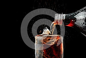 Pour soft drink in glass with ice splash on dark background.