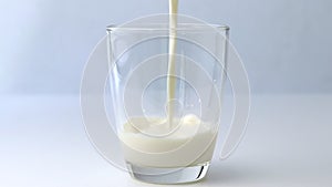 Pour the splash of milk into a clear glass on a white table.