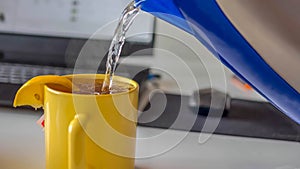 Pour tea, aromatic tea with lemon, the kettle pours water into a mug,steaming tea