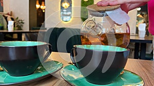 Pour tea into two cups Young woman hands holding thermos cup. pouring hot beverage to mug on picnic outdoors