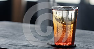 pour tonic water over clear ice ball in tumbler glass on black oak table