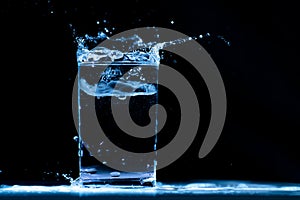 Pour water into glass on black background photo