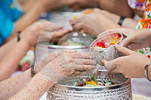 Pour water on the hands of revered elders and gives blessing in