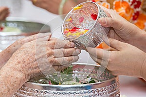 Pour water on the hands of revered elders and gives blessing in