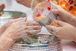 Pour water on the hands of revered elders and gives blessing in photo