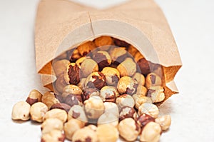 Poured beautifully laid out hazelnuts from a brown paper bag on a white table