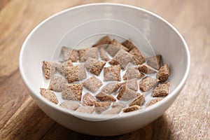 Poured with milk chcolate cereal pillow in white bowl on table