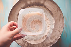 Pouring active yeast in a bowl with flour