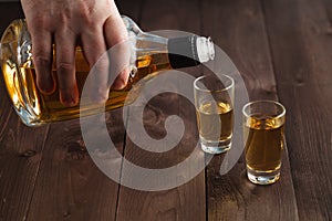 Pouring alcohol in shot glass on wooden table