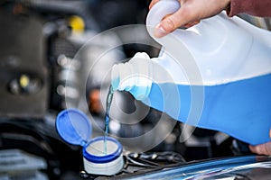 Pouring antifreeze. Filling a windshield washer tank with an antifreeze in winter cold weather.