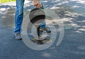 Pouring asphalt sealant on driveway