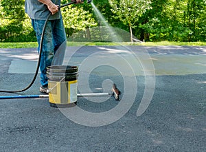 Pouring asphalt sealant on driveway