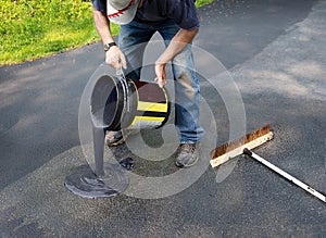 Pouring asphalt sealant on driveway