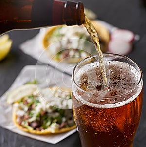 Pouring beer in front of mexican tacos photo