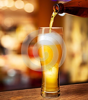 Pouring beer in glass on bar desk