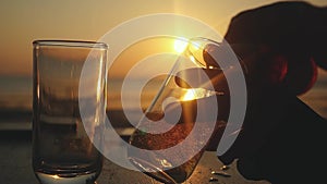 Pouring Beer in a Glass on a Beach at beautiful Sunset through the sun with lens flare effects in slow motion. 1920x1080