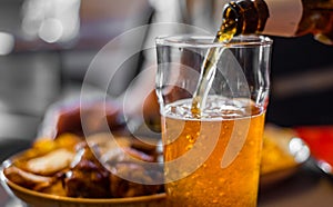 Pouring beer in glass from bottle on bar