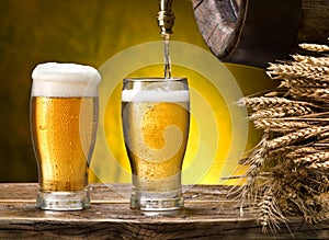 Pouring into beer glass. Glasses of beer and cask on the wooden table