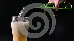 Pouring beer into a glass from green bottle, slow motion