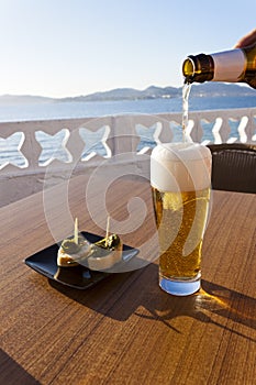 Pouring beer in a glass near the sea.