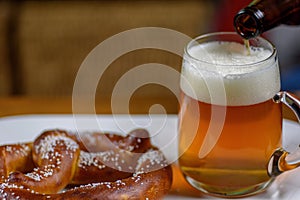 pouring beer into a large glass mug on plate with warm soft pretzel appetizer