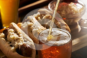 Pouring beer into mug with bratwursts in background