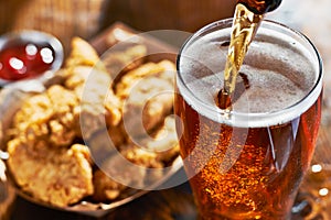 Pouring beer into mug with fried chicken tenders in background