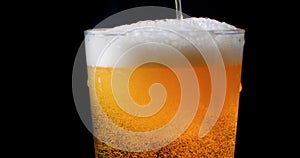 Pouring beer on a pint glass with black background