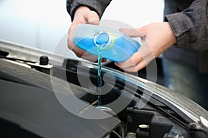 Pouring blue antifreeze liquid for washing car glass closeup