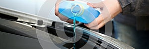 Pouring blue antifreeze liquid for washing car glass closeup