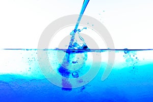 Pouring blue liquid into clear water