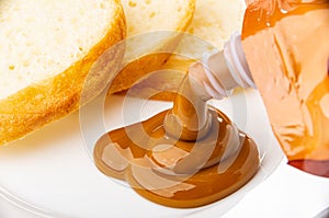 Pouring boiled condensed milk from pack in plate with slices of bread